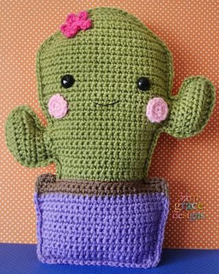 Kawaii amigurumi ragdoll style crochet pattern for a cactus with a smiling face, eyes, and a pink flower on top, housed in a purple crochet basket.
