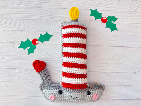 Kawaii amigurumi ragdoll style crochet pattern for a candlestick on a wooden background with holly leaves and berries.