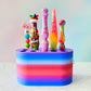 Colorful crochet hook stand with various colorful crochet hooks against a gradient background