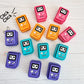Colorful Game Boy keychain clickers on a light wooden surface with 'Click Click' text.