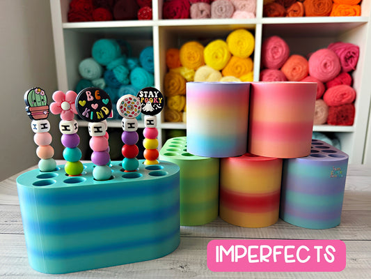 Colorful crochet hook holders on a wooden surface with yarn rolls in the background.