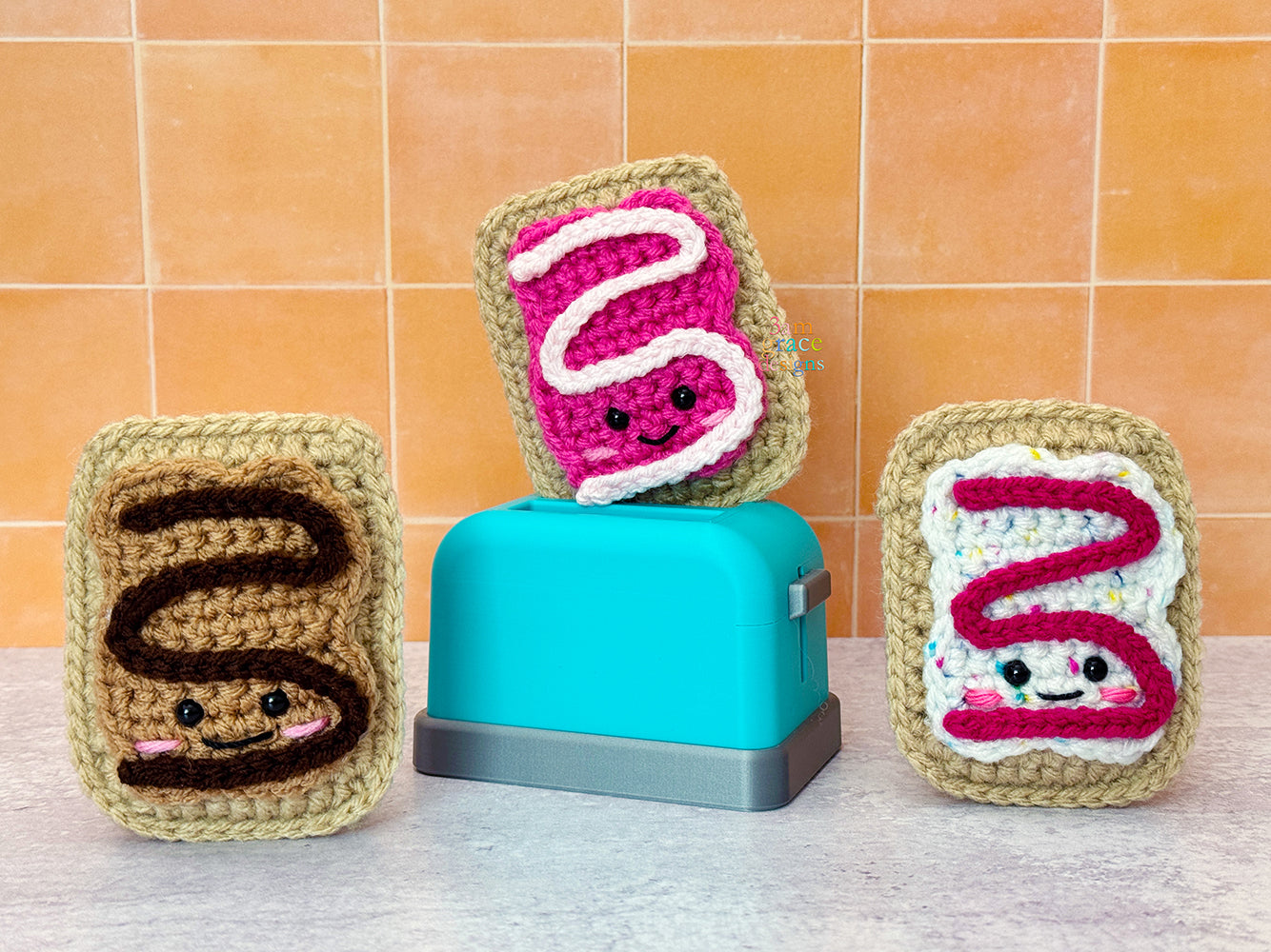 Small crocheted pop tarts on a cement surface with orange tile background
