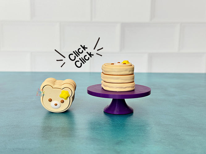 Bear-shaped pancake fidget clicker on a purple stand against a tiled wall background.