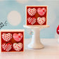 Heart-shaped donut box fidget clickers on a wooden surface with a blurred background