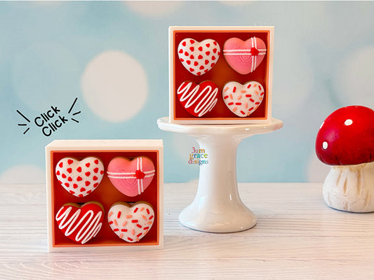 Heart-shaped donut box fidget clickers on a wooden surface with a blurred background
