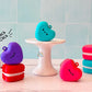 Heart macaron clicker keychain in purple, red, turquoise, and pink with a blue tile background