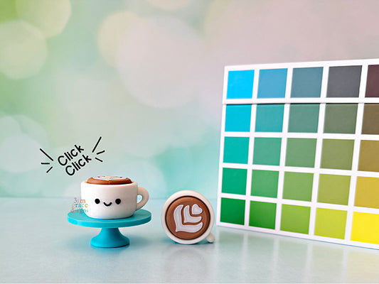 Latte coffee cup clickers on turquoise stand with colorful cube and bokeh background.