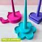 3d printed yarn spinner tool in shape of heart, flower, and cat in bright colors. Pictured on a light wooden surface