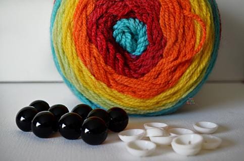 Set of 10 pair of 18mm safety eyes for crochet projects on a white background with yarn decoration.