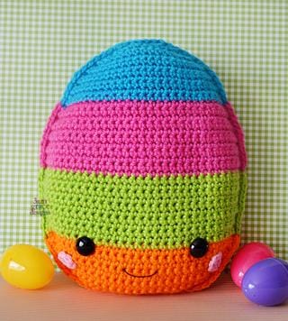 Kawaii amigurumi ragdoll style crochet pattern for an Easter egg-shaped pillow with colorful stripes, resembling a kawaii cuddler, displayed with colorful eggs and a smiling face.
