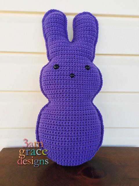 Kawaii amigurumi ragdoll style crochet pattern for a purple marshmallow bunny  with a simple facial feature design, posed against a neutral background.